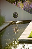 RICHARD JACKSONS GARDEN. DESIGNED BY CLARE MATTHEWS : WATER FEATURE - RECTANGULAR POND/POOL WITH METAL SAIL AND WATERFALL. REFLECTION