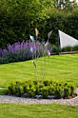 RICHARD JACKSONS GARDEN: EVENING LIGHT ON LAWN AND BORDER PLANTED WITH NEPETA WALKERS LOW  WATER RILL AND METAL SAILS  BOX BALLS AND METAL SCULPTURE. DESIGNER: CLARE MATTHEWS
