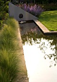 RICHARD JACKSONS GARDEN. DESIGNED BY CLARE MATTHEWS - WATER FEATURE - RECTANGULAR POOL/ POND WITH STIPA TENUISSIMA  METAL SAIL WITH WATERFALL. REFLECTION