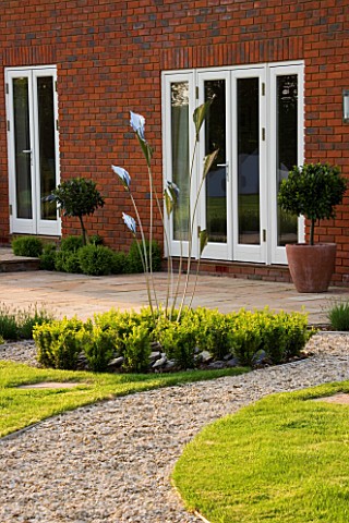 RICHARD_JACKSONS_GARDEN_DESIGNED_BY_CLARE_MATTHEWS__GRAVEL_PATH_PAST_LAWN_WITH_BOX_BALLS_AND_METAL_S
