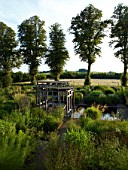 BURY COURT  HAMPSHIRE: FRONT GARDEN DESIGNED BY CHRISTOPHER BRADLEY-HOLE. LARGE SQUARE FORMAL POOL  WOODEN COVERED SEATING AREA AND PERENNIALS AND GRASSES