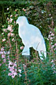 VEDDW HOUSE GARDEN  GWENT  WALES: DESIGNERS ANNE WAREHAM AND CHARLES HAWES - WOODEN CUT OUT BUZZARD SCULPTURE SURROUNDED BY ROSEBAY WILLOWHERB (EPILOBIUM ANGUSTIFOLIUM)