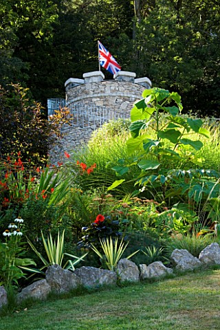 YEWBARROW_HOUSE_GARDENS__CUMBRIA__TROPICAL_BORDER_WITH_THE_NEW_ROUND_TOWER