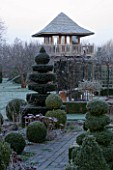 WOODPECKERS  WARWICKSHIRE  WINTER: THE FORMAL TOPIARY GARDEN IN FROST WITH SUMMERHOUSE TOWER BEHIND