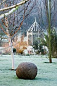 WOODPECKERS  WARWICKSHIRE  WINTER: FROSTY LAWN WITH WOODEN SUMMERHOUSE  BETULA HERGEST AND WOVEN WILLOW SCULPTURE