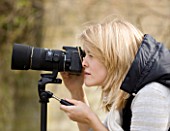 BLOND HAIRED GIRL WITH 35MM SLR DIGITAL CAMERA IN A GARDEN