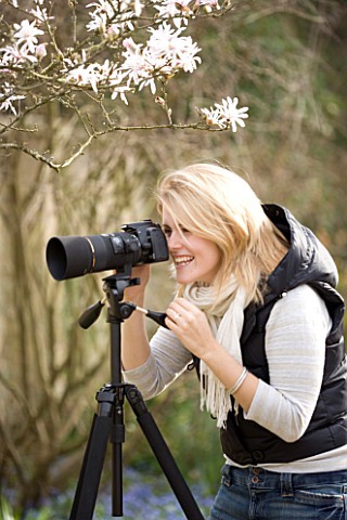 BLOND_HAIRED_GIRL_WITH_35MM_SLR_DIGITAL_CAMERA_IN_A_GARDEN