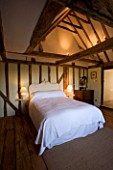 BOONSHILL FARM  EAST SUSSEX. INTERIOR OF BEDROOM WITH WOODEN FLOORBOARDS  EXPOSED BEAMS AND LINEN COVERED ARMCHAIRS AND MIRROR MADE FROM OLD WINDOW. DESIGNER: LISETTE PLEASANCE