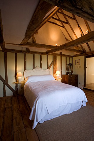BOONSHILL_FARM__EAST_SUSSEX_INTERIOR_OF_BEDROOM_WITH_WOODEN_FLOORBOARDS__EXPOSED_BEAMS_AND_LINEN_COV