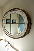 BOONSHILL FARM  EAST SUSSEX. INTERIOR OF BATHROOM WITH OVAL MIRROR MADE FROM OLD WINDOW ABOVE BATH. DESIGNER: LISETTE PLEASANCE