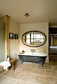 BOONSHILL FARM  EAST SUSSEX. INTERIOR OF BATHROOM WITH ROLLTOP (CLAWFOOT) BATH  WOODEN BENCH FROM INDIA  AND MIRROR MADE FROM OLD WINDOW. DESIGNER:  LISETTE PLEASANCE