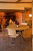 BOONSHILL FARM  EAST SUSSEX. INTERIOR OF KITCHEN WITH INGLENOOK FIREPLACE  TABLE AND CHAIRS  TRIPOD LAMP AND ORIGINAL BRICK FLOOR. DESIGNER: LISETTE PLEASANCE