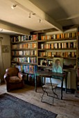BOONSHILL FARM  EAST SUSSEX. INTERIOR OF STUDY WITH BOOKSHELVES MADE FROM RECLAIMED JOISTS MADE BY MICK SHAW. OLD LEATHER ARMCHAIR AND OLD WOODEN DESK & CHAIR D: LISETTE PLEASANCE