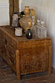 BOONSHILL FARM  EAST SUSSEX. ANTIQUE CHINESE CHEST STANDS ON ORIGINAL BRICK FLOOR WITH SPANISH POT AND ANTIQUE INDIAN CARVED STONE HEAD. DESIGNER : LISETTE PLEASANCE