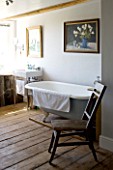 BOONSHILL FARM  EAST SUSSEX. INTERIOR OF BATHROOM WITH OLD ROLLTOP (CLAWFOOT) BATH AND ANTIQUE CHAIR FROM INDONESIA. DESIGNER : LISETTE PLEASANCE