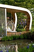 CHELSEA FLOWER SHOW 2007: GARDEN DESIGNED BY DIARMUID GAVIN. THE WESTLAND GARDEN. PAVILLION CLAD IN RED CEDAR WOOD WITH BUBBLE CHAIR AND RECYCLED TIMBER DECKING OVERLOOKING POND