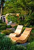 CHELSEA FLOWER SHOW 2007: GARDEN DESIGNED BY DIARMUID GAVIN. WESTLAND GARDEN. RECYCLED TIMBER CHAIRS OVERLOOK LUSH PLANTED GARDEN WITH RED CEDAR PAVILLION IN BACKGROUND