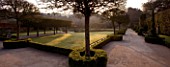 HOLKER HALL  CUMBRIA - THE SUNKEN GARDEN AT DUSK WITH BOX HEDGING  LAWN AND STATUARY. FORMAL GARDEN