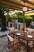 CORFU  GREECE. MALAMA HOUSE NEAR BARBATI. PATIO DINING AREA WITH TABLE AND CHAIRS AND BARBEQUE SET FOR ALFRESCO DINING. EVENING LIGHT  ROMANTIC  AMBIENCE  RELAXING  RELAXED