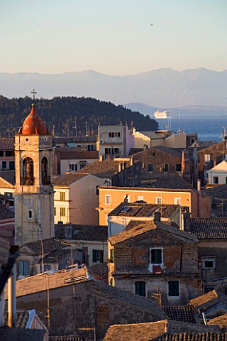 CORFU__GREECE_VIEW_OF_CORFU_TOWN_ROOFTOPS_AT_SUNSET_WITH_CORFU_MOUNTAINS_BEHIND