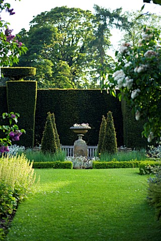 WARDINGTON_MANOR_GARDEN__OXFORDSHIRE_GRASS_PATH_LEADS_TO_AN_URN_ENCLOSED_BY_YEW_HEDGING_SPRING