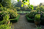 MARINERS GARDEN  BERKSHIRE. DESIGNER FENJA ANDERSON - VIEW INTO THE ROSE GARDEN TO THE WATER LILY POOL WITH HERON SCULPTURE. ROSES FANTIN LATOUR  FELICIA AND PROSPERITY