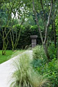 CONTEMPORARY TOWN/CITY/URBAN GARDEN DESIGNED BY CHARLOTTE SANDERSON: BORDER WITH GRASSES AND LIMESTONE PATH LEADING TO URN ON PLINTH. FOCAL POINT