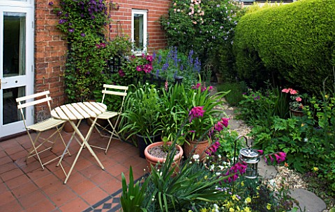 AMELIA_HEATH_GARDEN__1__CROSS_VILLAS__SHROPSHIRE_PATIO_BESIDE_THE_HOUSE__WOODEN_TABLE_AND_CHAIRS__PE