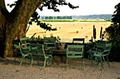 DESIGNER DOMINIQUE LAFOURCADE  PROVENCE  FRANCE - A PLACE TO SIT  GREEN CHAIRS AROUND A STONE TABLE WITH VIEW OUT TO COUNTRYSIDE BEYOND AND PLANE TREE. PATIO. TERRACE
