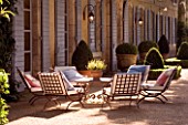 DESIGNER DOMINIQUE LAFOURCADE  PROVENCE  FRANCE - PROVENCAL FARMHOUSE WITH BLUE SHUTTERS  GRAVEL TERRACE WITH METAL TABLE AND CHAIRS WITH CUSHIONS. A PLACE TO SIT. EVENING LIGHT