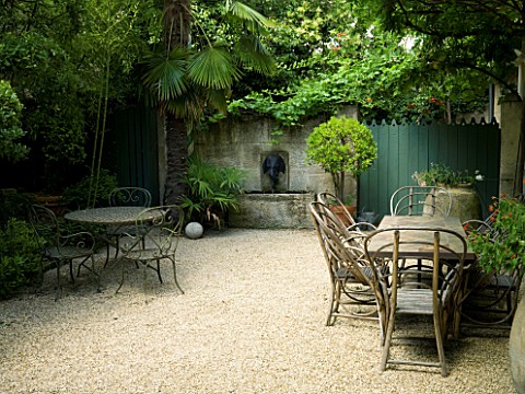 DESIGNER_DOMINIQUE_LAFOURCADE__PROVENCE__FRANCE__GRAVEL_COURTYARD_WITH_TABLE_AND_CHAIRS_AND_STONE_WA