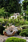 PROVENCE  FRANCE. GARDEN OF MARCO NUCERA. BEAUTIFUL WOODEN SEAT SCULPTURE BY MARCO NUCERA WITH CLIPPED TREES IN THE BACKLGROUND