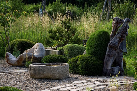 PROVENCE__FRANCE_GARDEN_OF_MARCO_NUCERA_CLIPPED_BOX__STONE_WATER_CONTAINER_AND_BEAUTIFUL_WOODEN_SCUL