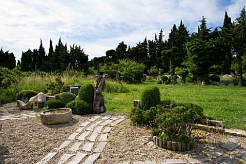 PROVENCE__FRANCE_GARDEN_OF_MARCO_NUCERA_GRAVEL_GARDEN_WITH_WOODEN_SCULPTURE__STONE_WATER_TROUGH__WOO
