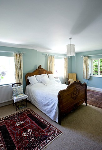 DESIGNER_CLARE_MATTHEWS__DEVON_BLUE_AND_WHITE_THEMED_BEDROOM_WITH_WOODEN_BED_AND_BLUE_HYDRANGEA_FLOW