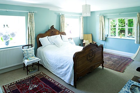 DESIGNER_CLARE_MATTHEWS__DEVON_BLUE_AND_WHITE_THEMED_BEDROOM_WITH_WOODEN_BED_AND_BLUE_HYDRANGEA_FLOW