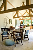 CLARE MATTHEWS HOUSE  DEVON. KITCHEN EXTENSION WITH EXPOSED ROOF BEAMS  FARMHOUSE TABLE AND BENCHES  CREAM LIMESTONE FLOOR. DESIGNER: CLARE MATTHEWS