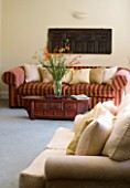 CLARE MATTHEWS HOUSE  DEVON. INTERIOR OF LIVING ROOM WITH CREAM AND RED & GOLD STRIPED SOFA AND VASE OF CROCOSMIA ON COFFEE TABLE. DESIGNER CLARE MATTHEWS