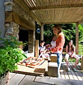 DESIGNER CLARE MATTHEWS: DEVON GARDEN. OUTDOOR SEATING AREA AND OUTDOOR KITCHEN. CLARE ABOUT TO PUT PIZZA IN THE OVEN