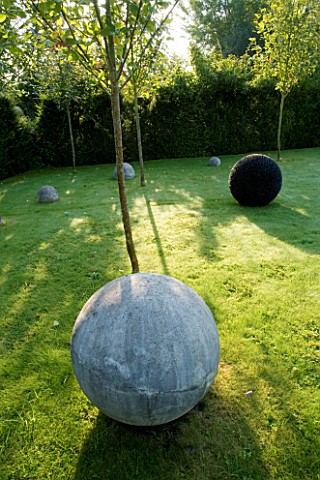 DAVID_HARBER_SUNDIALS_SPHERICAL_STONE_SCULPTURES_ON_LAWN_WITH_BLACK_PEBBLED_SCULPTURE_DARK_PLANET_ON