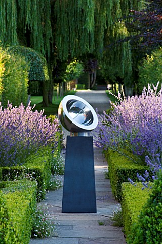 DAVID_HARBER_SUNDIALS_CHALICE_SUNDIAL_ON_PATH_IN_FORMAL_GARDEN_WITH_BOX_HEDGING__LAVENDER_ON_LEFT_AN