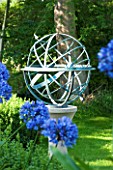 DAVID HARBER SUNDIALS: ARMILLARY SPHERE SUNDIAL ON STONE PLINTH WITH AGAPANTHUS IN FOREGROUND