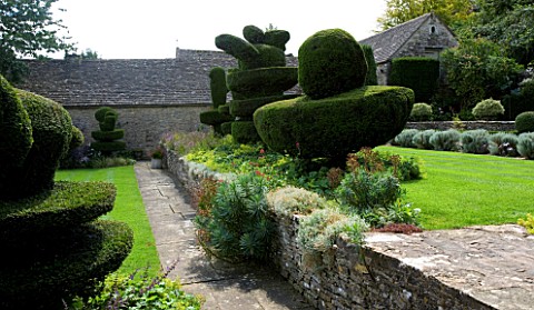 THROUGHAM_COURT__GLOUCESTERSHIRE_DESIGNER_CHRISTINE_FACER_THE_FRONT_LAWN_WITH_YEW_TOPIARY_SHAPES