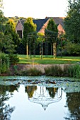 WILKINS PLECK  STAFFORDSHIRE: THE LAWN IN FRONT OF THE HOUSE WITH METAL GAZEBO REFLECTED IN THE LAKE