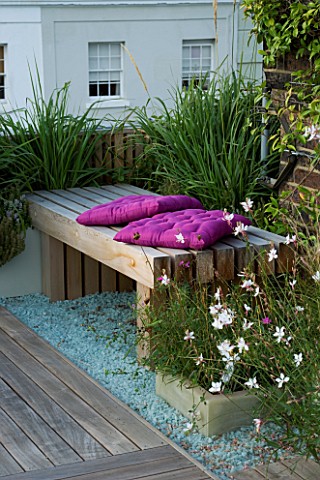 ROOF_GARDEN__HOLLAND_PARK__LONDON_DESIGNER_CHARLOTTE_ROWE_WOODEN_BENCH__MAUVE_CUSHIONS_ON_DECKED_TER