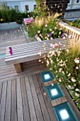 ROOF GARDEN  HOLLAND PARK  LONDON. DESIGNER: CHARLOTTE ROWE.WOODEN BENCH  CANDLES  IPE DECKED TERRACE  WHITE LED LIGHTING  RAISED BEDS WITH GAURA LINDHEIMERI WHIRLING BUTTERFLIES