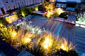 ROOF GARDEN  HOLLAND PARK  LONDON. DESIGNER: CHARLOTTE ROWE. DECKED TERRACE AT NIGHT WITH LED LIGHTING AND BLUE GLASS GRAVEL  STIPA TENUISSIMA  GAURA LINDHEIMERI