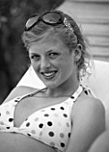 GIRL (AGED 15) SMILING IN A DECKCHAIR. SUNGLASSES. BLACK AND WHITE IMAGE