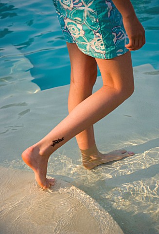 GIRL_WITH_TATTOO_ON_LEG_WALKING_IN_A_SHALLOW_POOL