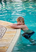 BOY (AGED 13) LEANING ON THE EDGE OF A SWIMMING POOL